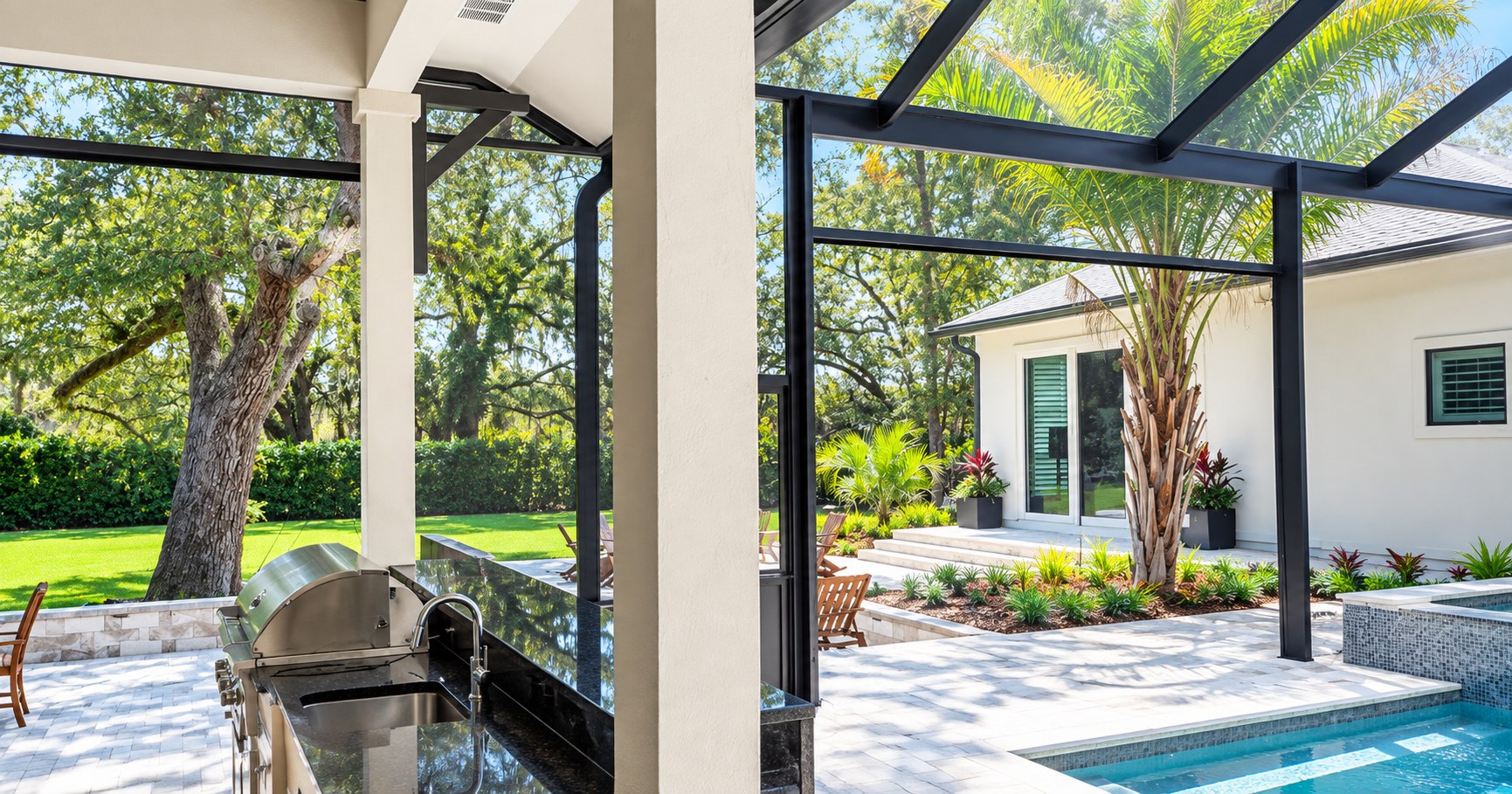 Pool cage with motorized screens beside a covered outdoor kitchen